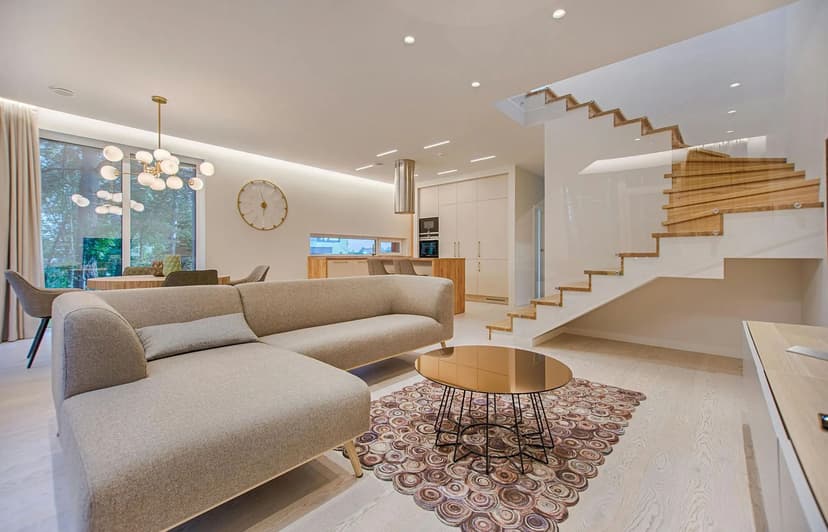 Modern living room with stylish sofa, glass coffee table, and staircase in elegant home interior.