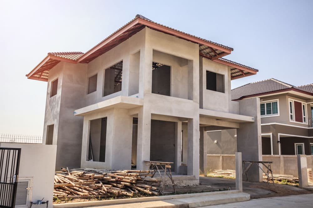 Newly constructed two-story house with unfinished exterior and scaffolding materials nearby.